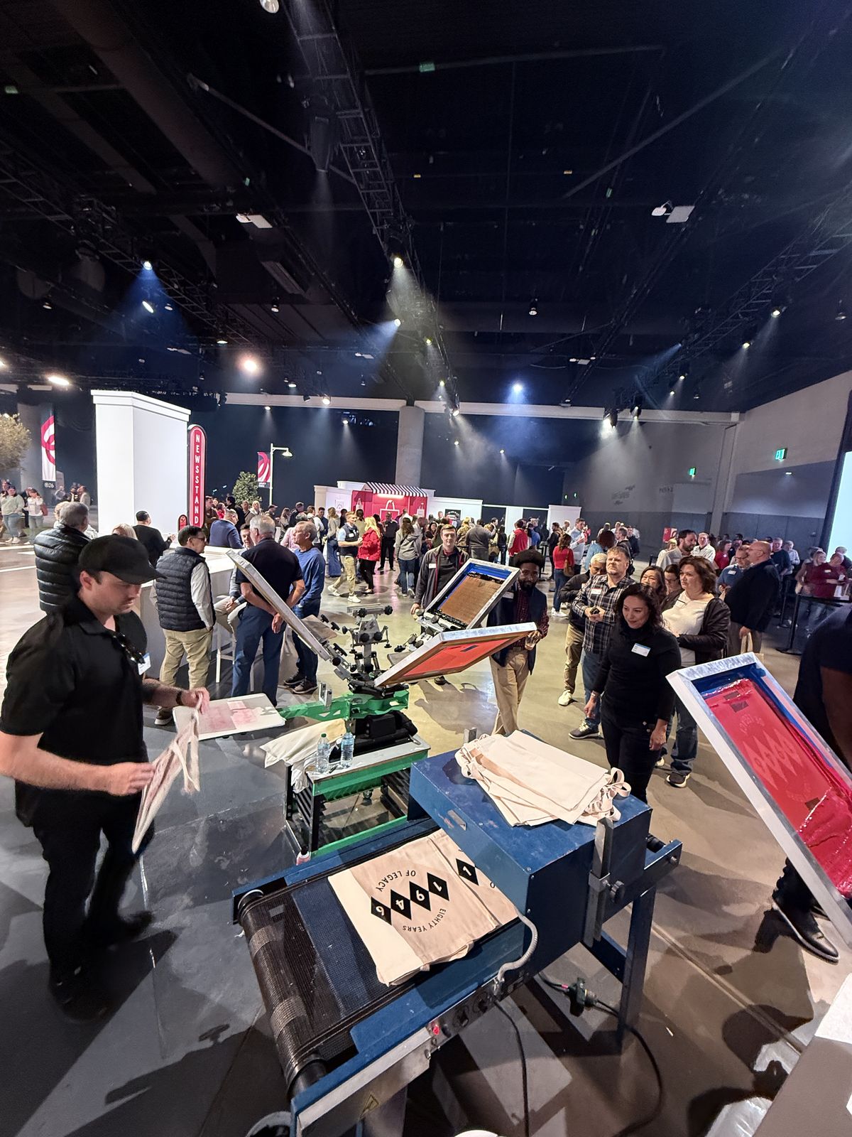Convention hall with multiple live printing stations and attendees watching
